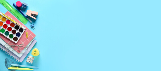 School supplies with paint palette on blue background. Top view