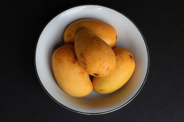 Bowl of mangoes on dark background
