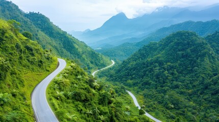 A scenic view of a winding road gracefully meandering through lush, green mountains and hills, illustrating a peaceful, natural landscape perfect for exploration.
