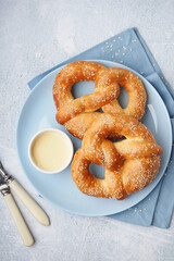 Plate with tasty pretzels and condensed milk on light background, closeup