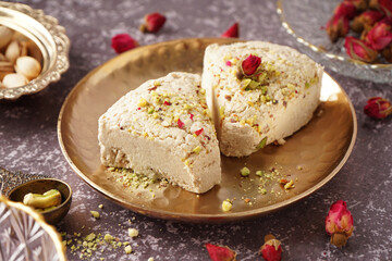 Plate with pieces of tasty Tahini halva on grunge background