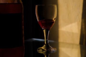 a glass of wine stands on a table in low light