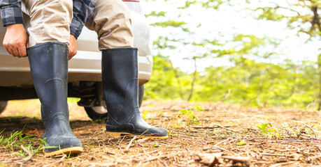Close-up of a man's legs adjusting rubber boots, ready to work in the field, biologist