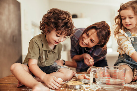 Happy mother baking with her kids at home kitchen