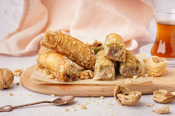 Wooden board with tasty baklava on light background