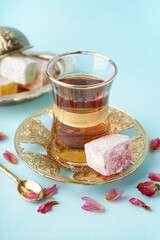 Glass of tea and Turkish delight on light blue background