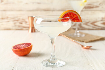 Glass of martini with grapefruit on white wooden table