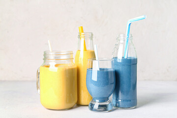 Glasses and bottles of colorful smoothie on white table