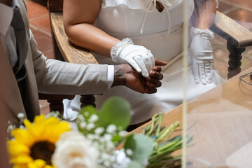 Black male hand and white gloved female hand hold each other with love on wedding day