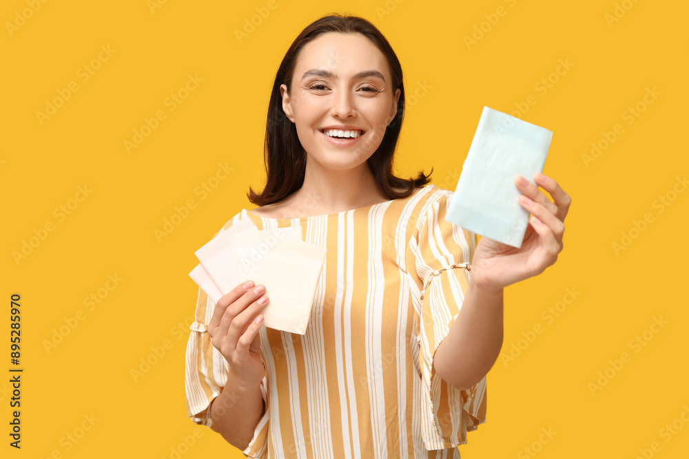 Wall mural beautiful young woman with menstrual pads on yellow background