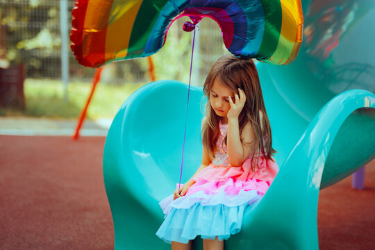 Unhappy Little Girl Holding a Helium Balloon Sitting Alone. Depressed child having maladjustment problems not fitting in
