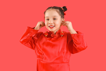 Cute little Asian girl with Chinese symbols on red background. New Year celebration