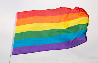 Huge flag of LGBT attached on long handle against background of clear bright sky