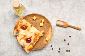 Wooden plate with delicious pizza slices, scoop and bottle of oil on white grunge background