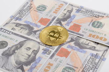 Golden symbolic coin Bitcoin on banknotes of one hundred dollars. Exchange bitcoin cash for a dollars. Cryptocurrency on US dollar bills. Savings, investments concept. Digital modern method of payment