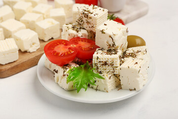Plate with delicious cut feta cheese, olive and tomatoes on white grunge background