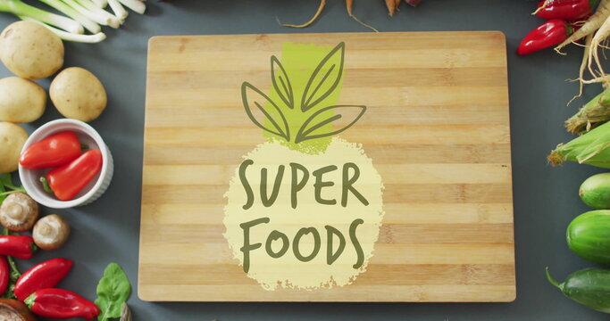 Super Foods text image over wooden cutting board surrounded by fresh vegetables