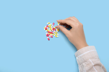 Female hand with different pills on blue background