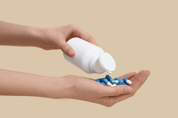 Female hands with jar of pills on beige background