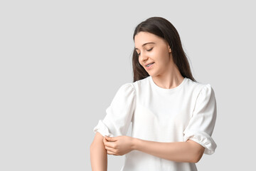 Pretty young woman in stylish white long-sleeve with rolled up sleeves on grey background