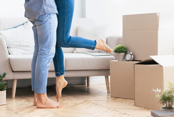 A couple celebrates moving into their new home by embracing, the woman playfully lifting her leg...