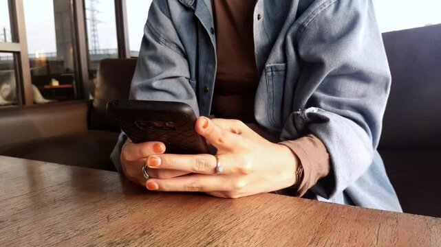 closeup of a woman's hands typing and chatting using her cell phone on the table