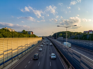 Passenger cars on a multi-line highway in the city at sunset.