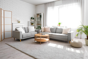 Cozy sofa with cushions and coffee table with magazine in living room