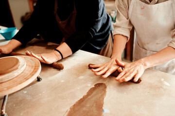 Hands, clay roll and pottery class in studio with design, mold and ceramic creation hobby at table. Teach, workshop and handmade art with artisan, people and craft with mud and creative learning - Powered by Adobe