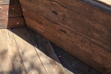 Wooden floors in corners decorate the exterior under sunlight and shadow. Outdoor wallpaper. Light and dark brown shades. 