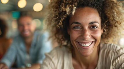 Obraz premium A woman with curly hair is enjoying a casual outing, likely at a cafe or restaurant, with lights out of focus in the background, highlighting her relaxed and joyful mood.