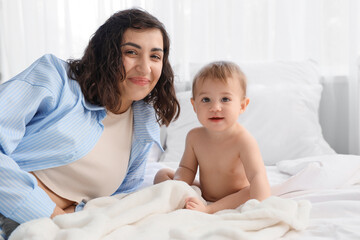 Mother with her little baby after bathing in bedroom