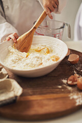 Hands, flour and eggs in bowl for baking, cake and dessert in France on table with spoon and person. Wheat, process and cooking in kitchen on counter in bakery for cookie, breakfast and learning