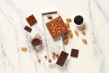 Sweet chocolate with almond nuts, hazelnuts and cocoa powder on white background