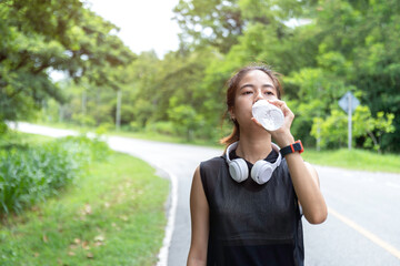 A young woman pauses her morning exercise to take a refreshing sip of water