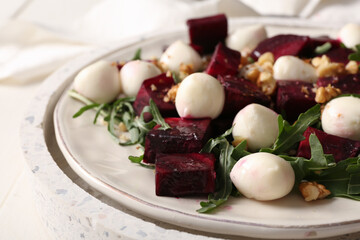 Plate of fresh salad with beet and mozzarella cheese on white background, closeup