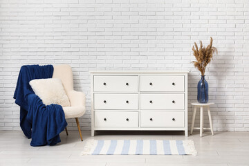 Modern chest of drawers with lamp, decor and coffee table in room