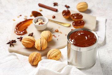 Board with tasty walnut shaped cookies, boiled condensed milk and ingredients on white grunge table