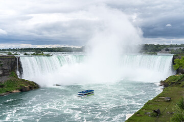 A tour boat cruises towards to mist at the base of the Horseshoe Falls in Niagara Falls New York