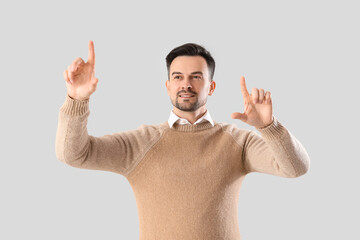 Young businessman using virtual screen on light background