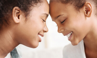 Sisterhood concept. Two african sisters with eyes closed touching each other with foreheads, close up