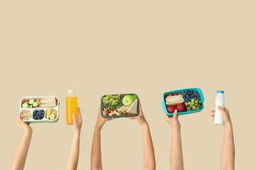 Female hands with school lunch boxes and drinks on beige background