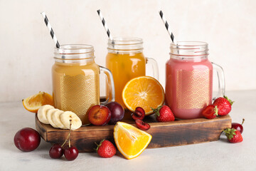Mason jars of fresh juice with different fruits on white background