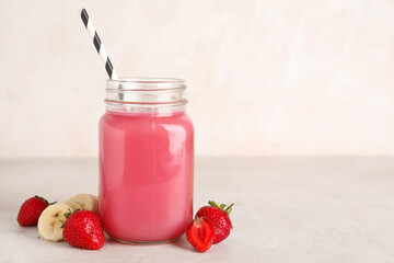 Mason jar of fresh strawberry juice with banana on white background