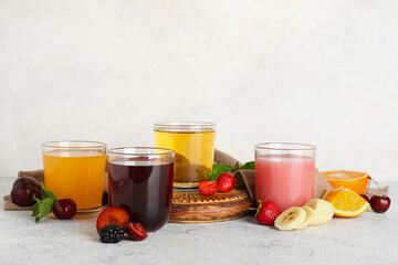 Glasses of fresh juice with different fruits and mint on white background