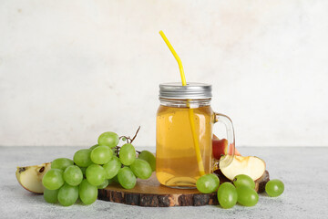 Mason jar of fresh apple juice with grapes on white background