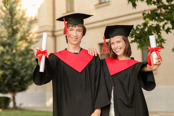 Graduating students with diplomas outdoors