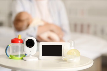 Baby monitor with bottle and pacifiers on table in bedroom, closeup