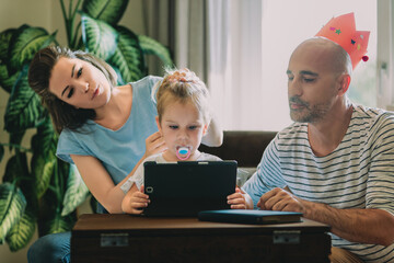 Young family using digital tablet at home for education and ente