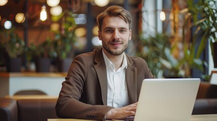 Fototapeta premium A confident businessman is working on his laptop in a modern cafe, symbolizing success, productivity, technology, and a modern work environment.